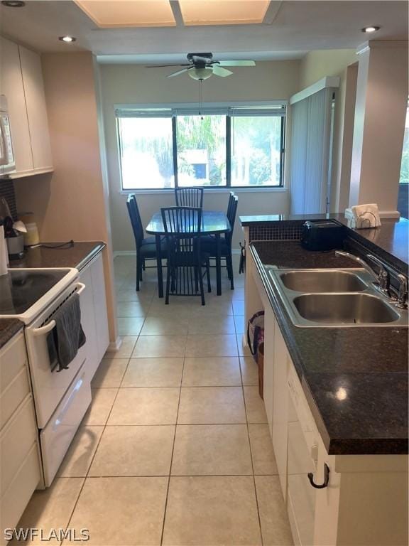 64 4th St Unit B201, Bonita Springs, FL 34134 - kitchen with white range with electric cooktop, a sink, dark countertops, a ceiling fan, and white cabinetry