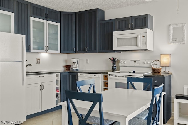 kitchen with white appliances, light tile patterned floors, a textured ceiling, white cabinetry, and sink