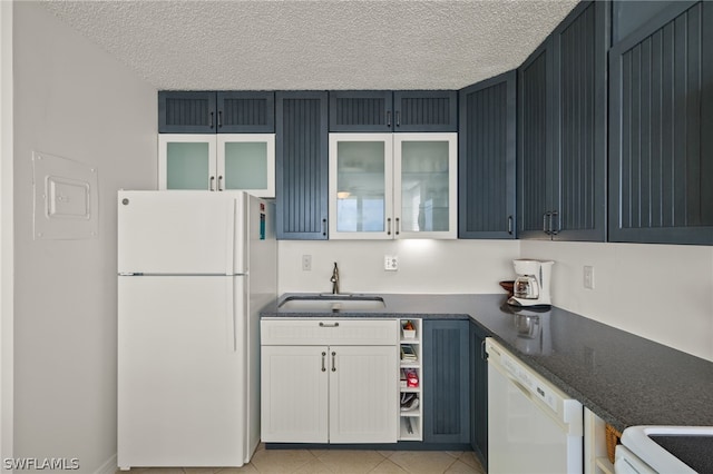 kitchen featuring white appliances, a textured ceiling, white cabinets, light tile patterned flooring, and sink