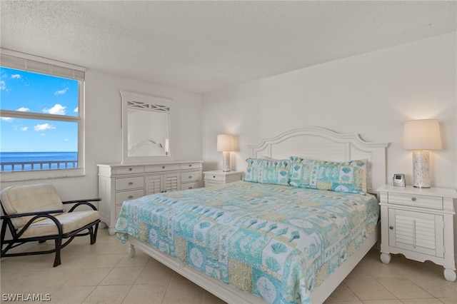 tiled bedroom featuring a textured ceiling and a water view