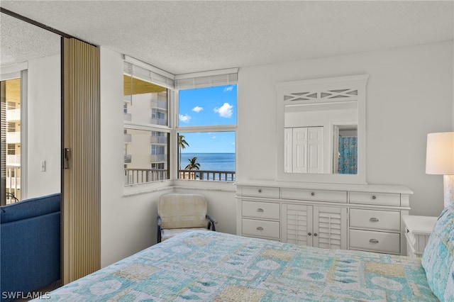 bedroom featuring a textured ceiling and a water view