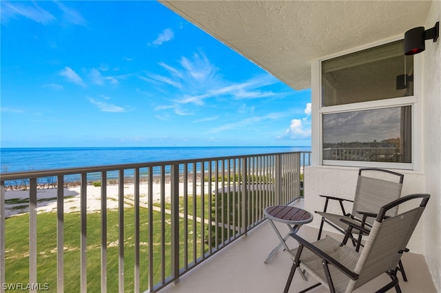 balcony featuring a view of the beach and a water view