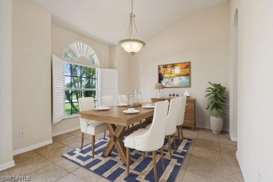 tiled dining space featuring vaulted ceiling