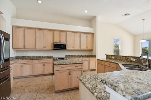 kitchen featuring decorative light fixtures, vaulted ceiling, sink, appliances with stainless steel finishes, and light brown cabinetry