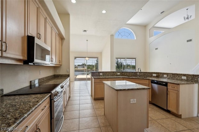 kitchen featuring decorative light fixtures, dark stone countertops, a center island, sink, and stainless steel appliances