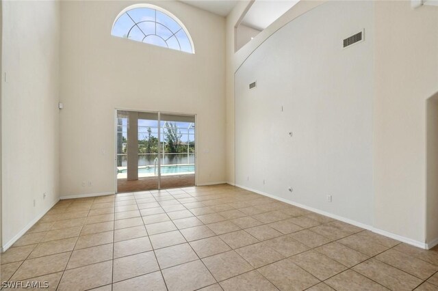 interior space with light tile patterned flooring, a healthy amount of sunlight, and a high ceiling