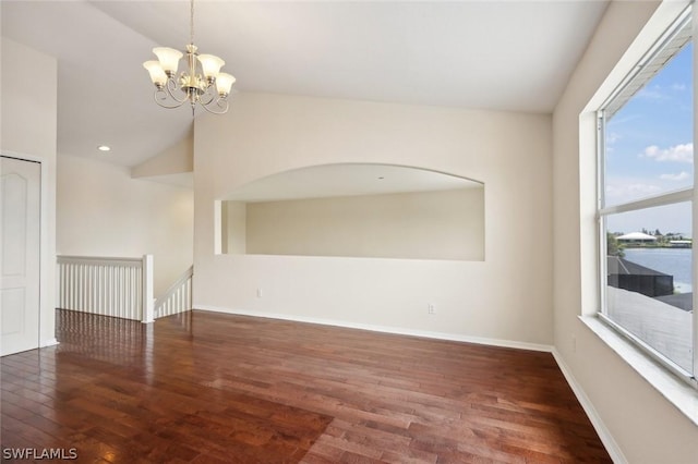 spare room with a notable chandelier, dark hardwood / wood-style flooring, a water view, and vaulted ceiling