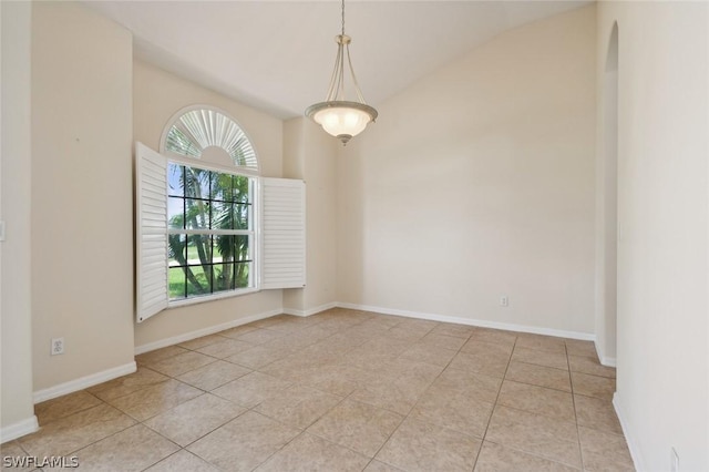 tiled empty room featuring lofted ceiling