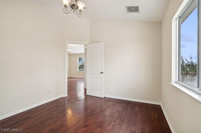 unfurnished room with dark hardwood / wood-style flooring, a healthy amount of sunlight, and a chandelier