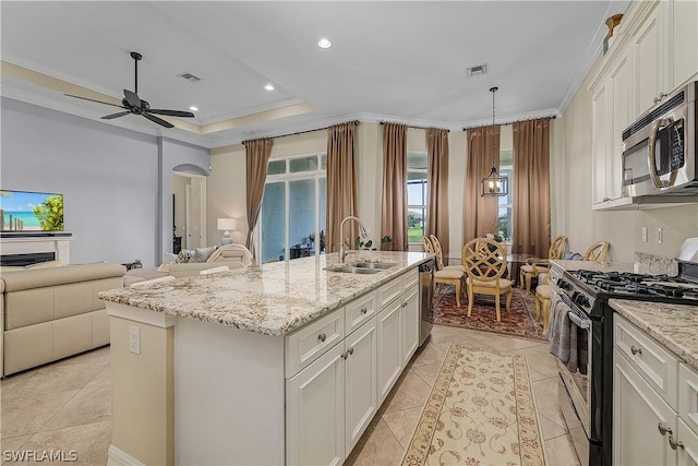 kitchen featuring a center island with sink, white cabinets, appliances with stainless steel finishes, and a tray ceiling