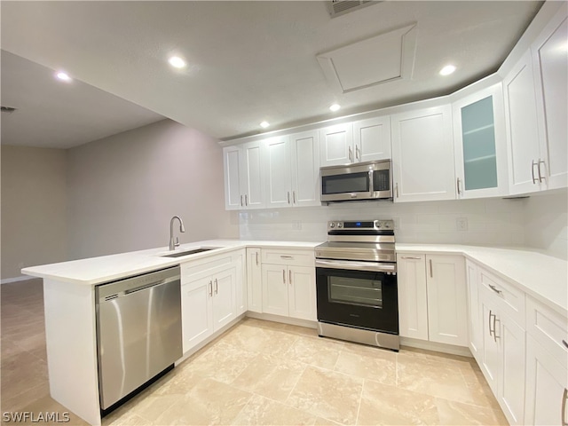 kitchen featuring kitchen peninsula, decorative backsplash, white cabinetry, sink, and stainless steel appliances