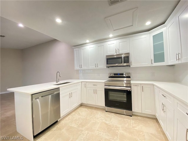 kitchen with sink, white cabinetry, appliances with stainless steel finishes, kitchen peninsula, and backsplash