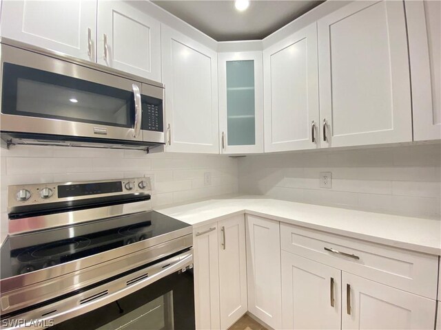 kitchen with tasteful backsplash, stainless steel appliances, and white cabinets