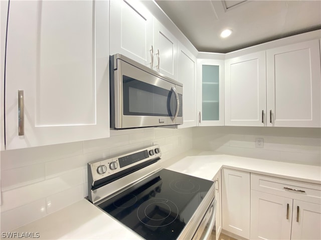 kitchen with decorative backsplash, white cabinets, and stainless steel appliances