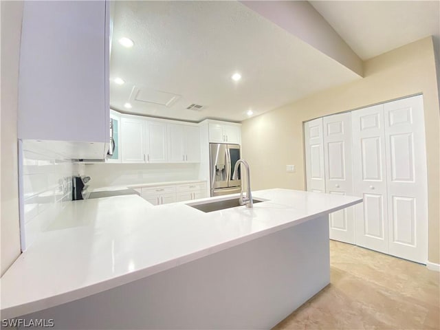 kitchen with white cabinets, range, kitchen peninsula, and stainless steel fridge