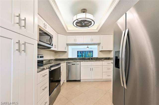 kitchen featuring a raised ceiling, white cabinetry, stainless steel appliances, and ornamental molding