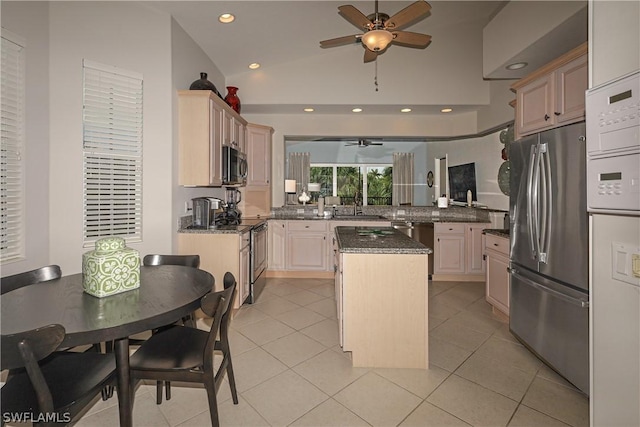 kitchen featuring sink, light tile patterned floors, appliances with stainless steel finishes, a kitchen island, and kitchen peninsula