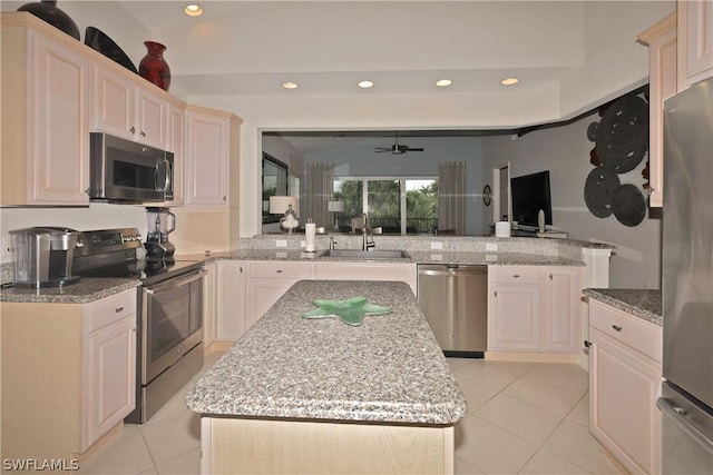 kitchen with sink, a center island, light tile patterned flooring, and appliances with stainless steel finishes