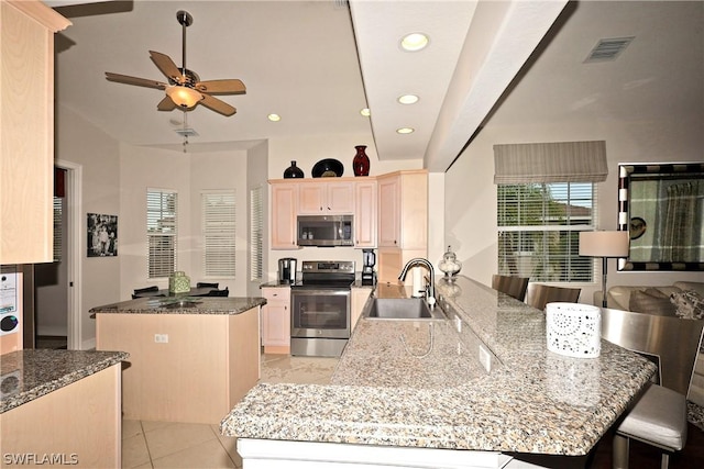 kitchen featuring kitchen peninsula, stainless steel appliances, and light stone counters