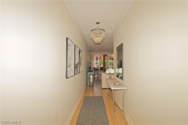 hall featuring a notable chandelier, light hardwood / wood-style floors, and crown molding