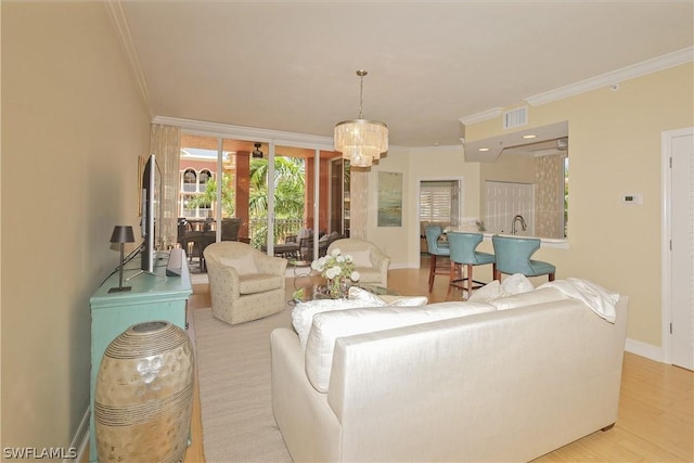 living room featuring ornamental molding, sink, light hardwood / wood-style floors, and a notable chandelier