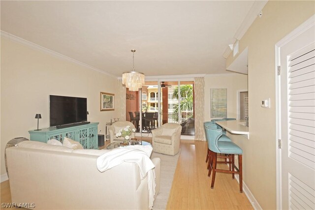 living room with light hardwood / wood-style flooring, ornamental molding, and an inviting chandelier