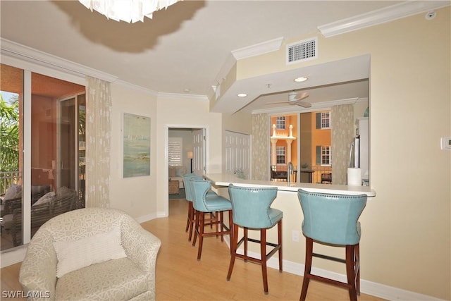 kitchen with kitchen peninsula, light hardwood / wood-style floors, and ornamental molding