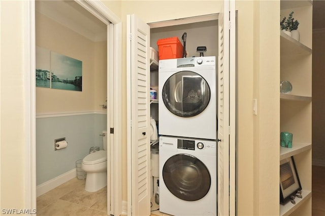 clothes washing area featuring stacked washer / drying machine and light tile patterned flooring