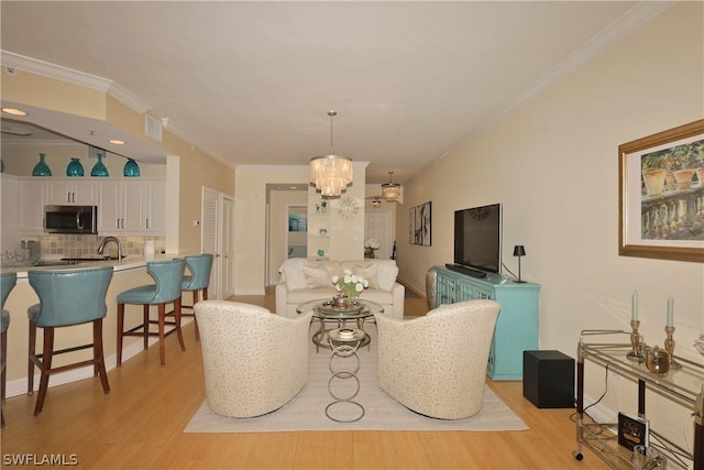 living room featuring crown molding, a chandelier, and light hardwood / wood-style floors