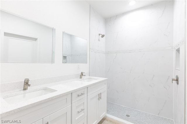 bathroom with tiled shower and dual bowl vanity