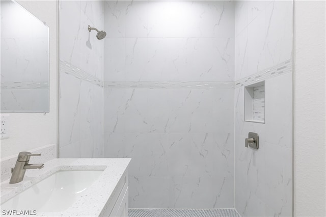 bathroom with tiled shower and vanity