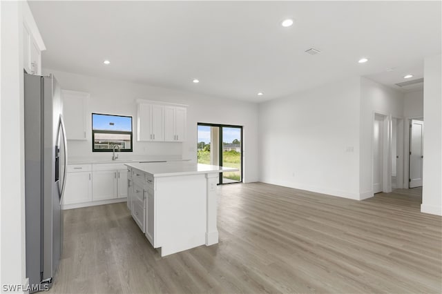 kitchen featuring white cabinetry, stainless steel refrigerator with ice dispenser, a center island, light hardwood / wood-style floors, and sink