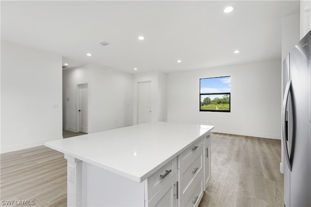 kitchen featuring a center island, light hardwood / wood-style flooring, stainless steel refrigerator, and white cabinets