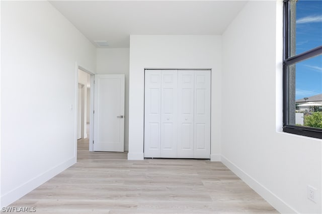 unfurnished bedroom with light hardwood / wood-style flooring and a closet