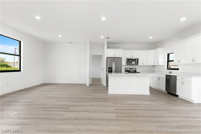 kitchen featuring a center island, white cabinets, light wood-type flooring, and stainless steel appliances