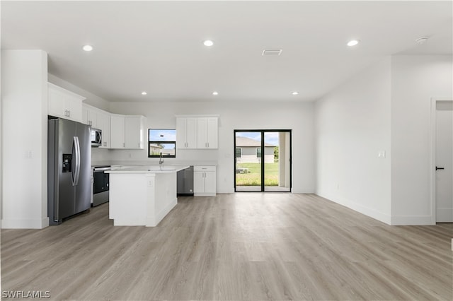 kitchen featuring white cabinetry, a kitchen island, light wood-type flooring, and stainless steel appliances