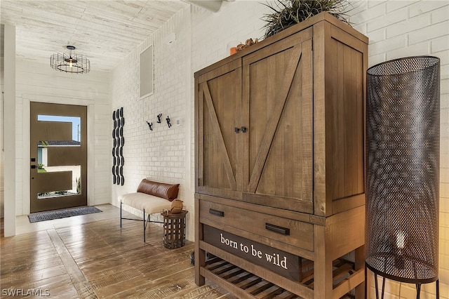 interior space featuring wooden ceiling, wood-type flooring, brick wall, and a chandelier