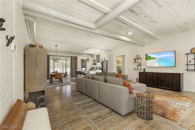 living room with hardwood / wood-style floors, beam ceiling, and brick wall