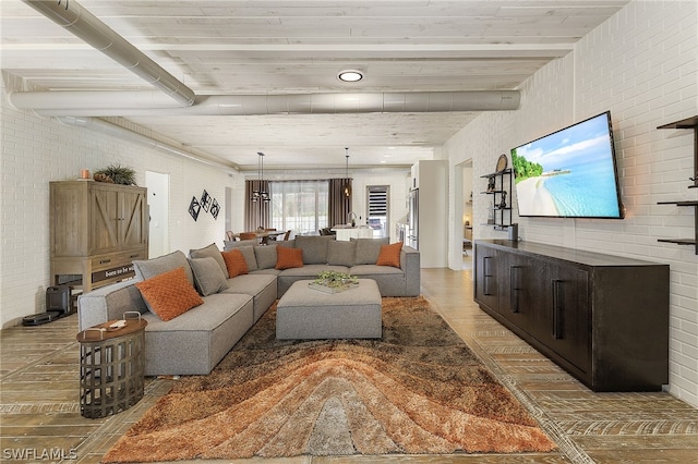 living room with beamed ceiling, light hardwood / wood-style floors, and brick wall