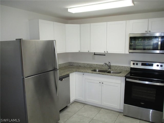 kitchen with sink, appliances with stainless steel finishes, white cabinets, stone countertops, and light tile patterned flooring