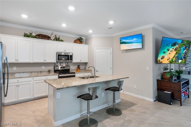 kitchen with a kitchen island with sink, sink, white cabinets, and appliances with stainless steel finishes