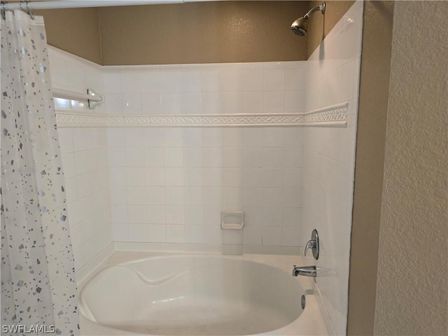 12940 Positano Cir Unit 201, Naples, FL 34105 - bathroom featuring shower / bath combination with curtain and a textured wall