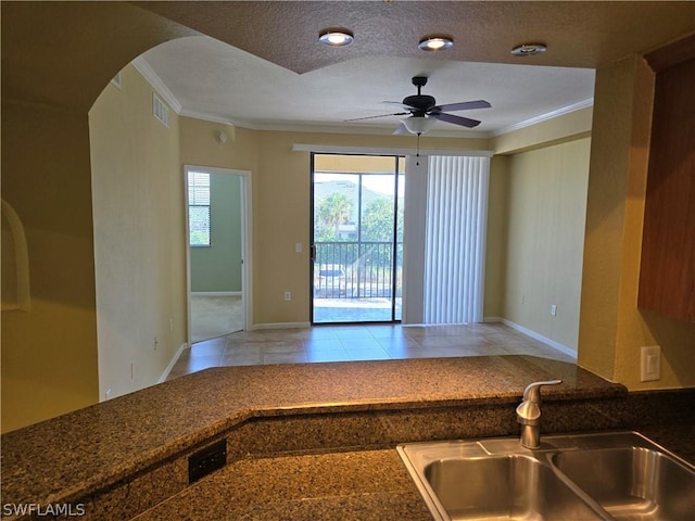 12940 Positano Cir Unit 201, Naples, FL 34105 - kitchen featuring crown molding, a sink, ceiling fan, dark countertops, and arched walkways