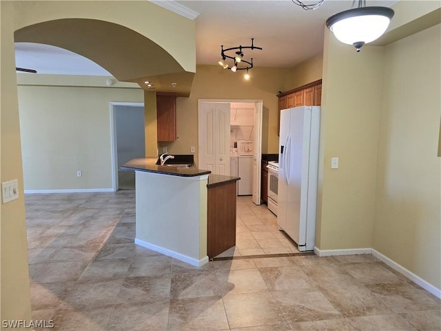 12940 Positano Cir Unit 201, Naples, FL 34105 - kitchen with white appliances, dark countertops, arched walkways, brown cabinetry, and baseboards