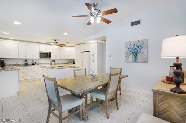 tiled dining area featuring ceiling fan, lofted ceiling, and sink