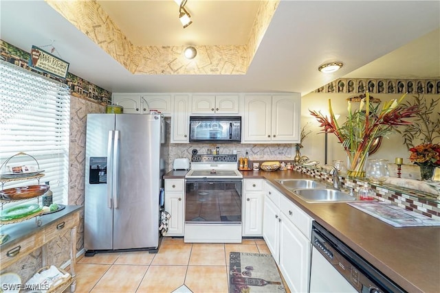 kitchen with stainless steel appliances, a tray ceiling, sink, white cabinets, and light tile patterned flooring