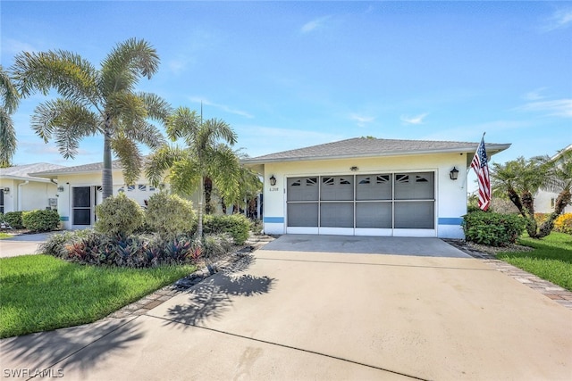 view of front of property featuring a garage, driveway, a front yard, and stucco siding