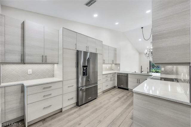 kitchen with light wood-style flooring, stainless steel appliances, gray cabinets, light stone countertops, and modern cabinets