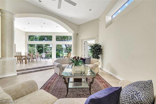 tiled living room with ornate columns, ceiling fan, and a high ceiling