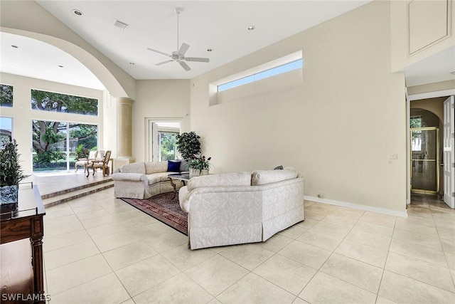 tiled living room featuring ceiling fan and a high ceiling